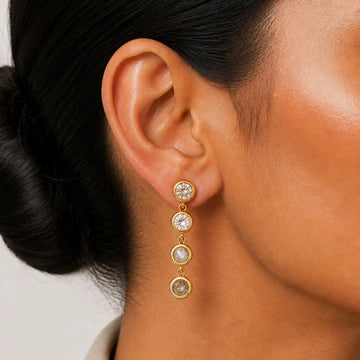 Close-up of an ear wearing a gold earring with multiple round stones.