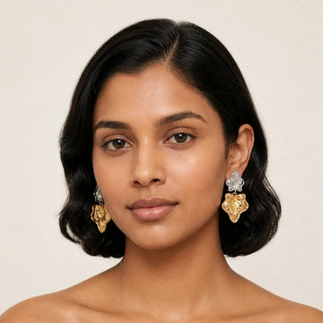 Woman wearing gold earrings with a neutral background