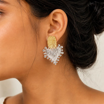 Close-up of a woman wearing a gold and silver heart-shaped earring.