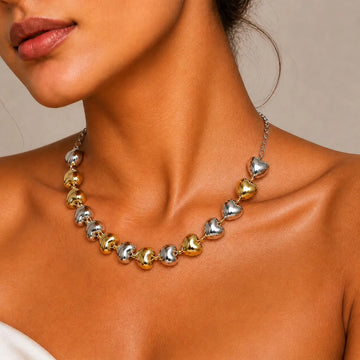 Close-up of a woman wearing a necklace with heart-shaped beads on a neutral background