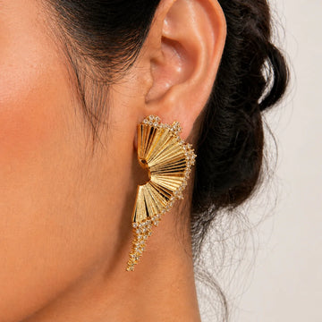 Gold earrings worn by a person with a neutral background
