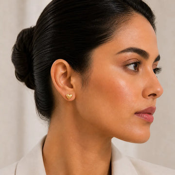 Close-up of a woman wearing a heart-shaped earring against a neutral background