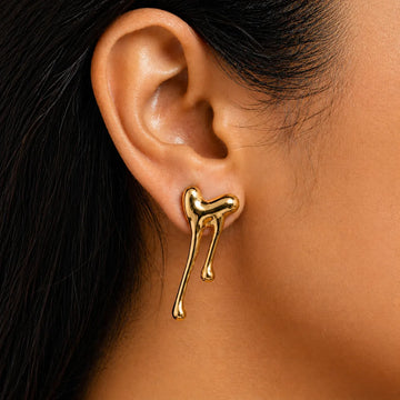 Gold dog-shaped earring worn by a person with black hair.
