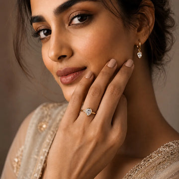 Woman wearing a diamond ring and earrings with a neutral background