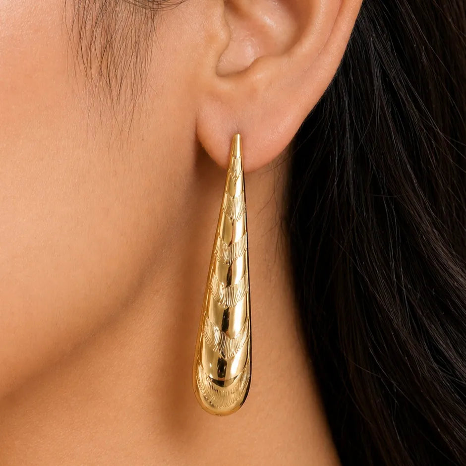 Gold earring worn by a person with dark hair.