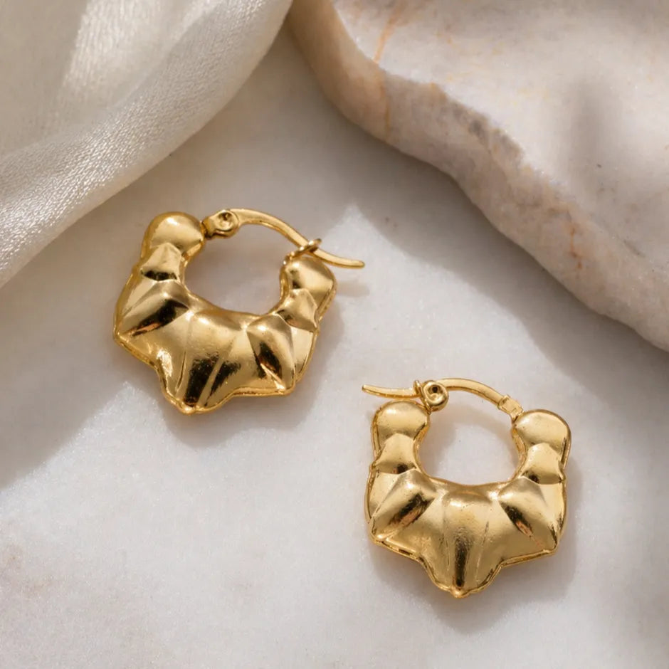 Gold hoop earrings on a light marble surface