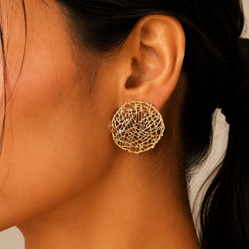 Close-up of a person wearing a gold textured earring.