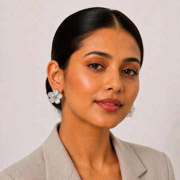 Woman wearing floral earrings against a plain background