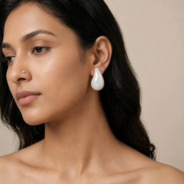 Woman wearing a pearl earring against a neutral background