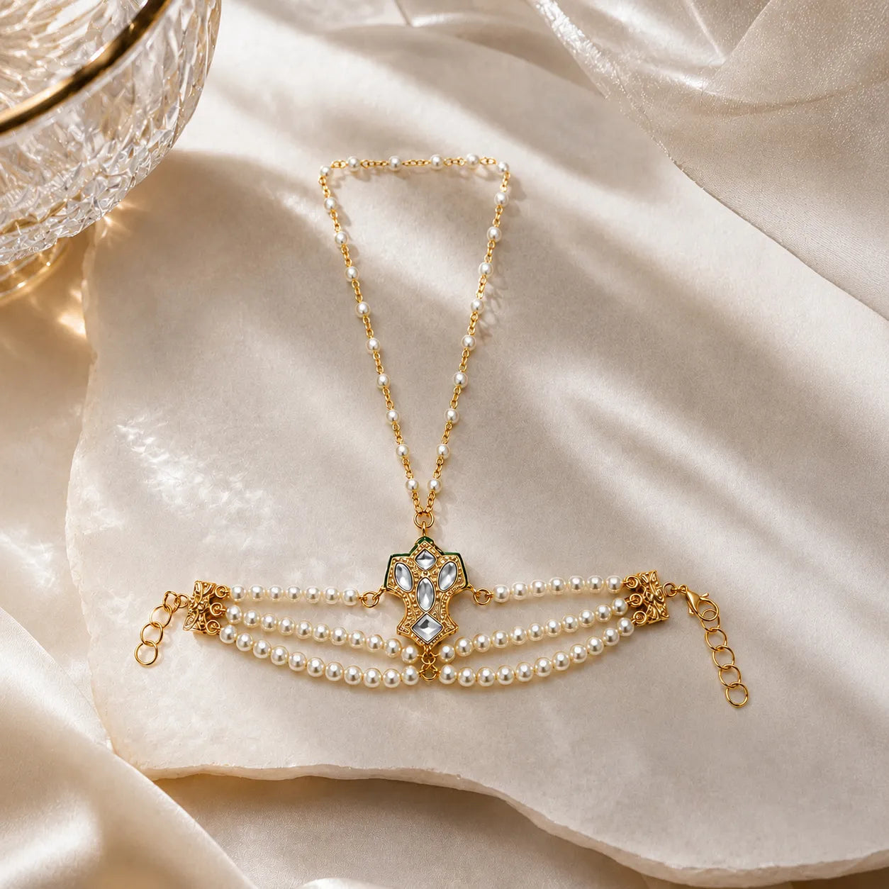 Gold haathphool with pearl accents on a beige fabric background