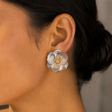 Close-up of a silver floral earring worn by a person.