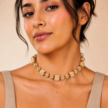 Woman wearing a gold necklace against a beige background