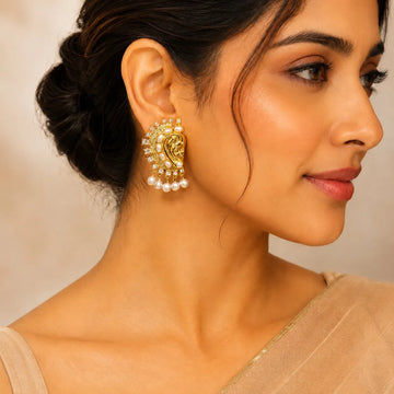 Woman wearing a gold and pearl earring with a neutral background