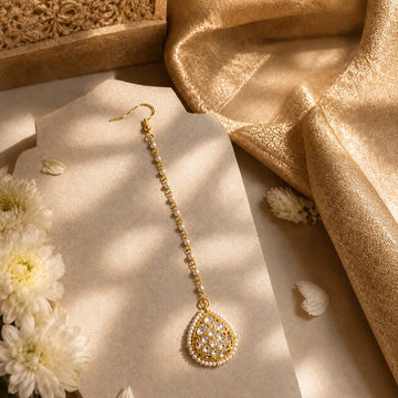 Gold earring on a white stand with a gold fabric background
