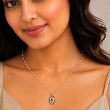 Close-up of a woman wearing a necklace with a pendant against a neutral background