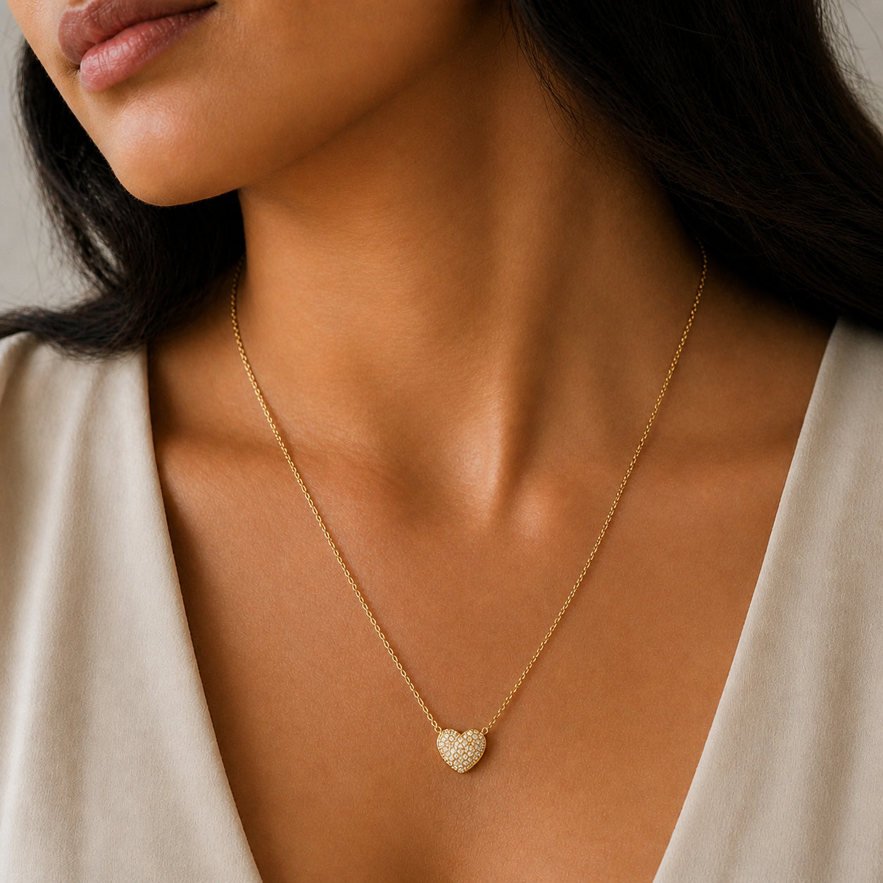 Close-up of a woman wearing a gold necklace with a heart pendant.