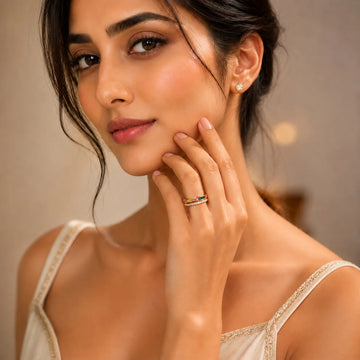 Woman wearing earrings and rings, touching her face with a neutral background
