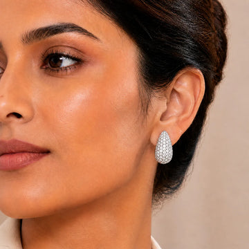 Close-up of a woman wearing a silver earring with a beige background