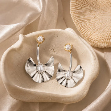 Pair of silver earrings with pearl-like centers on a beige fabric background