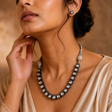 Close-up of a woman wearing a necklace and earrings against a warm-toned background