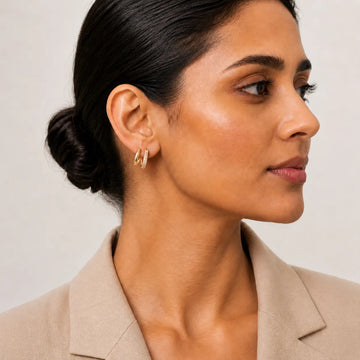 Woman wearing gold hoop earrings with a neutral background