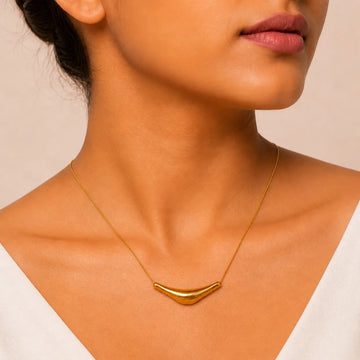 Gold necklace on a person with a neutral background