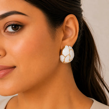 Close-up of a woman wearing a floral earring with a neutral background